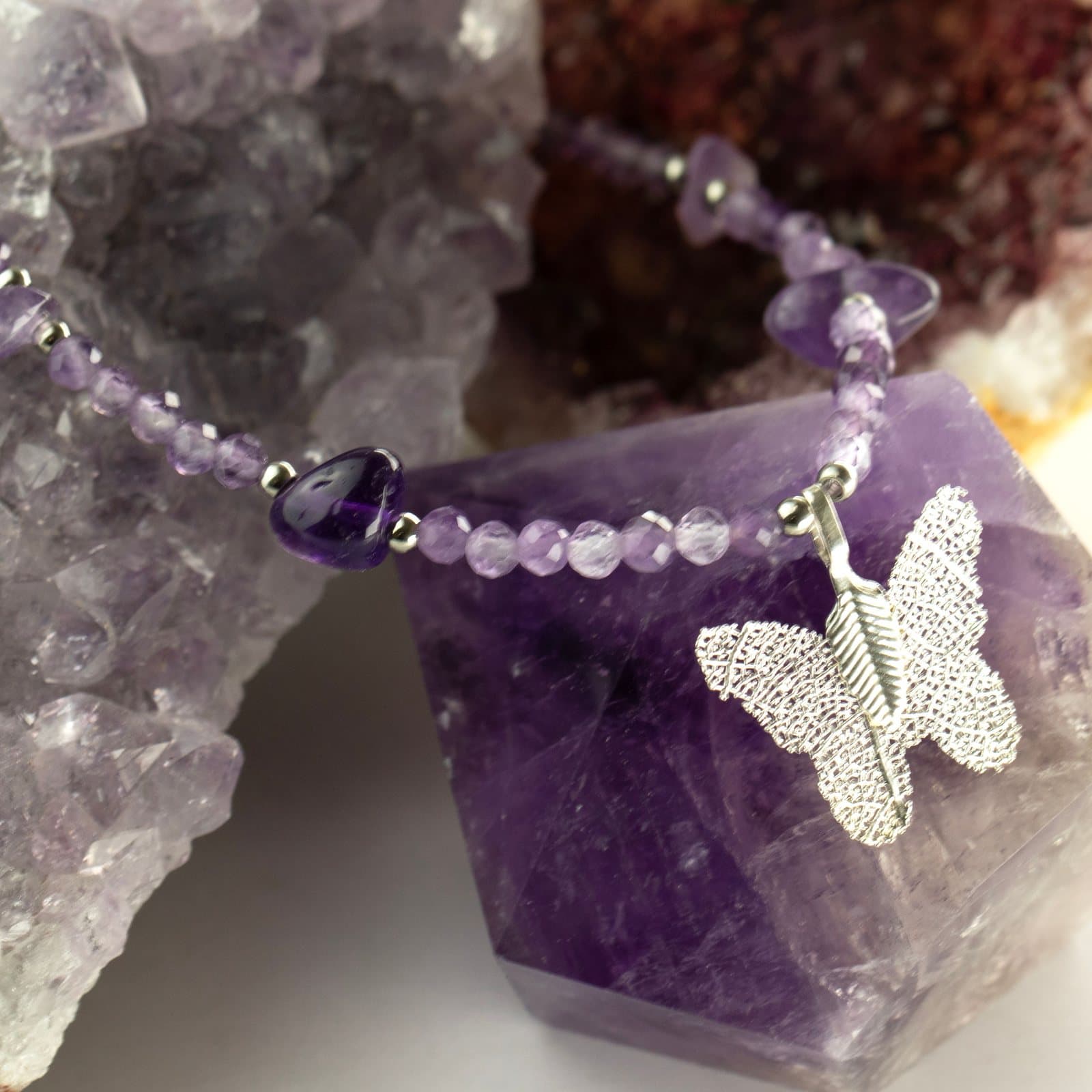 Faceted amethyst bead necklace with a silver butterfly pendant made from a leaf