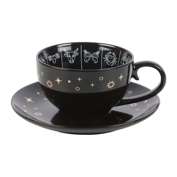 Black teacup and saucer with a white and gold zodiac wheel design