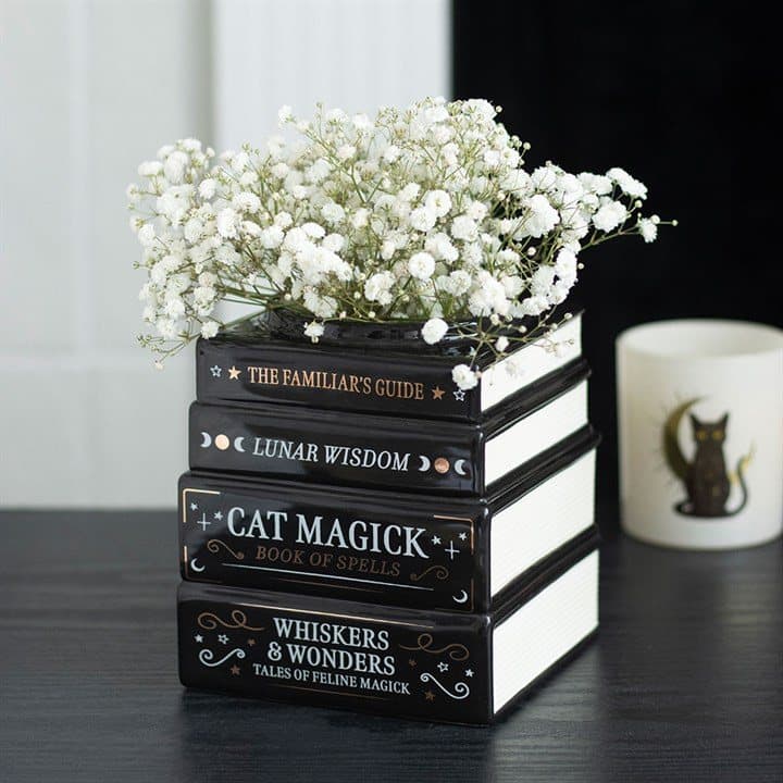 Black ceramic vase shaped like a stack of books with mystical titles