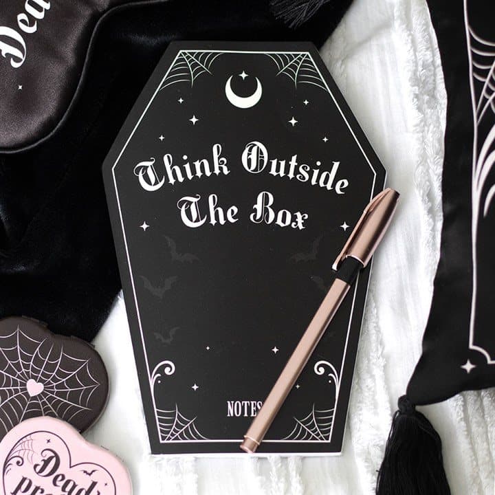 Black coffin shaped notebook with a soft cover and pink accents