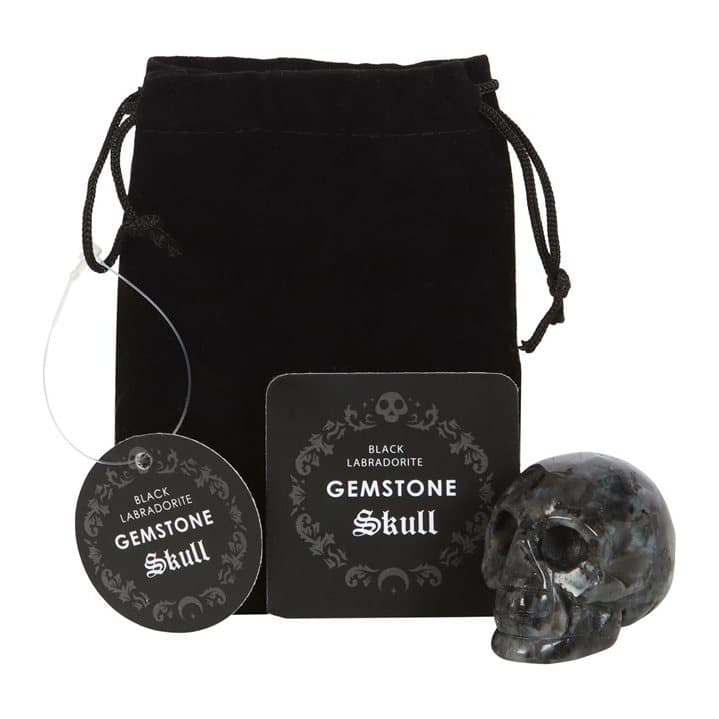 Black labradorite crystal skull beside a black drawstring pouch