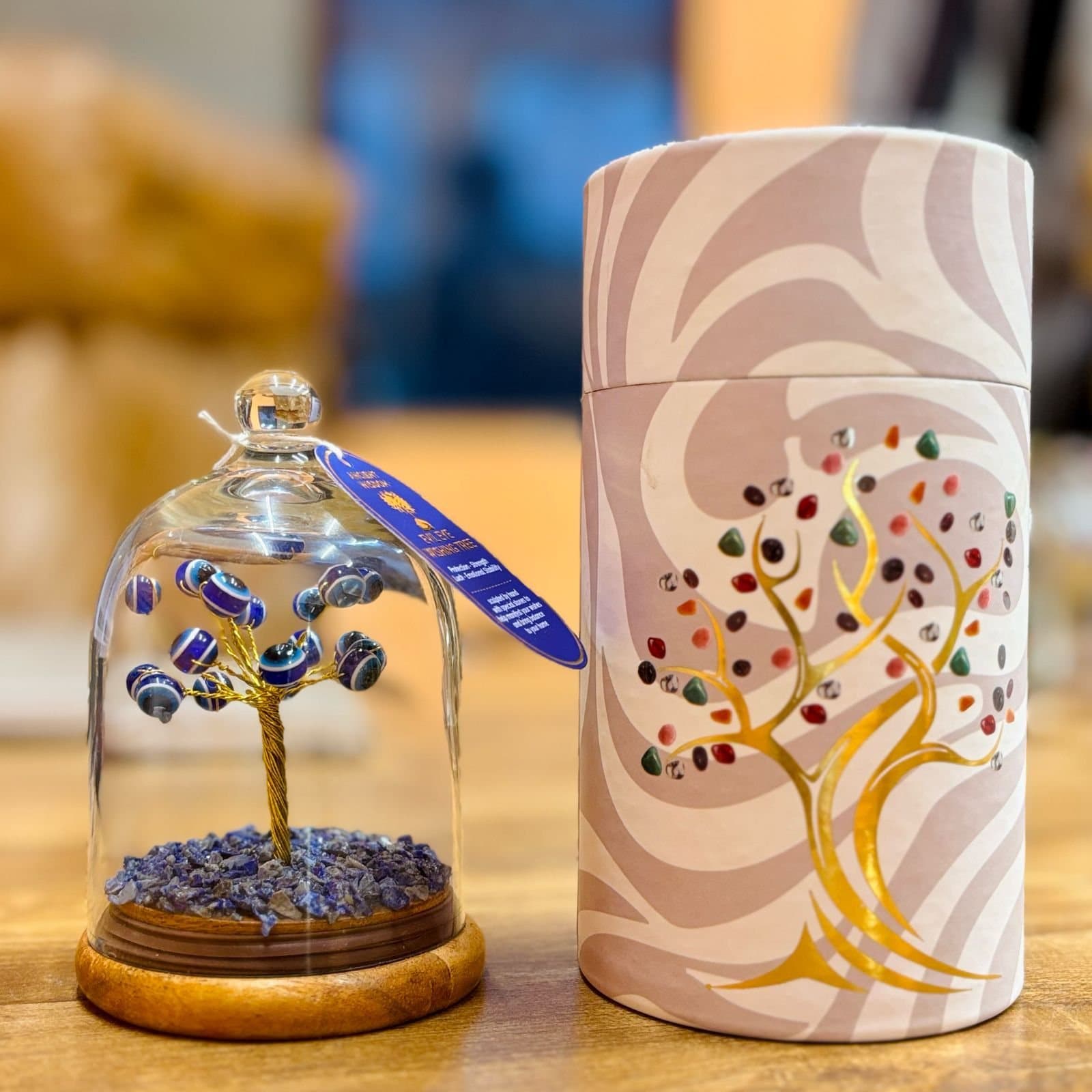 Evil eye bead tree on blue lapis lazuli chips under a glass dome on a wooden base
