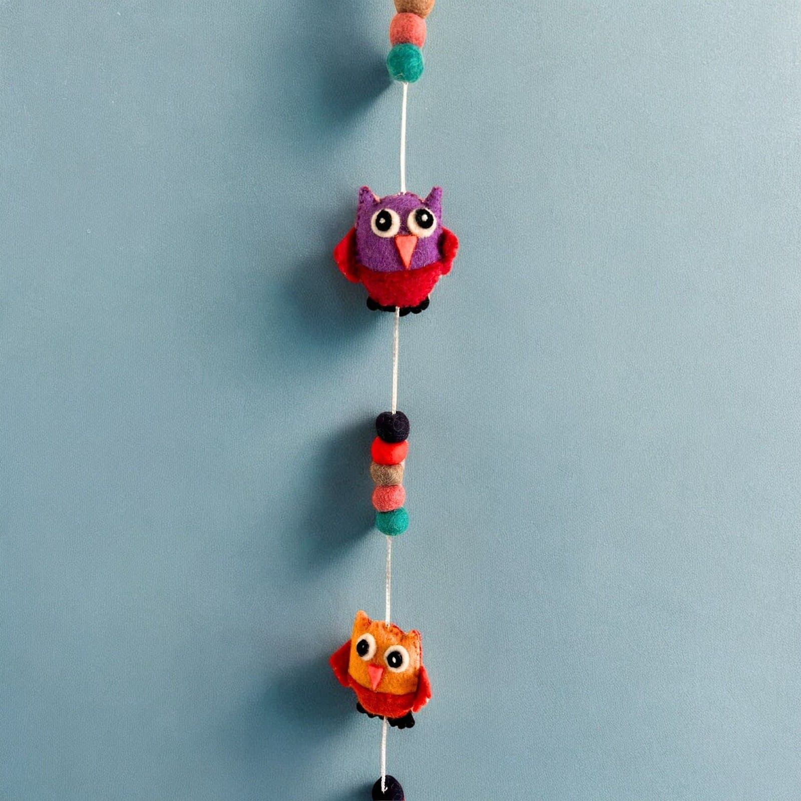 Long, narrow felt wall hanging with a run of soft felt shapes