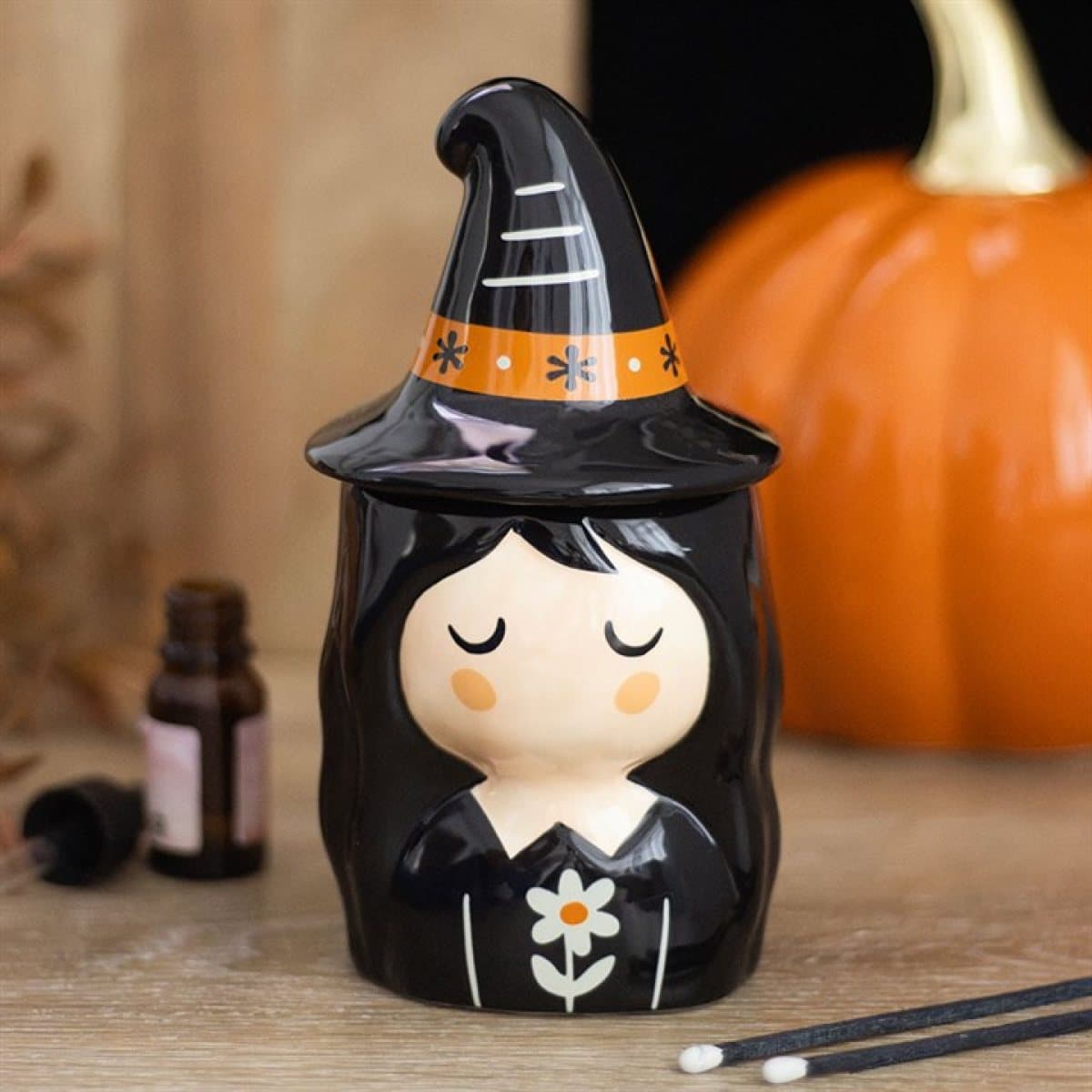 Ceramic witch oil burner with floral details, a pointed hat and a lid