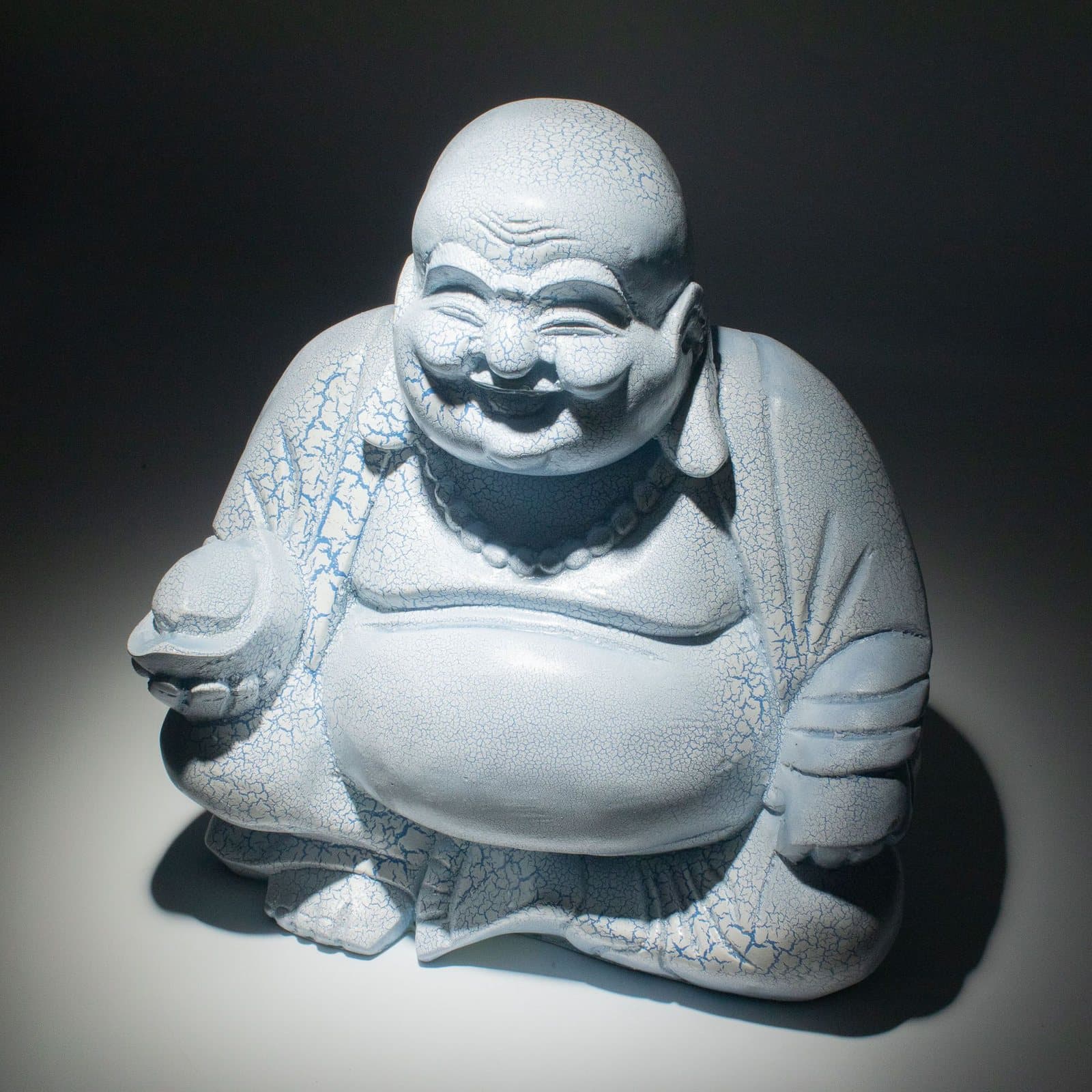 Glass Laughing Buddha lamp with a crackle finish on a round stand
