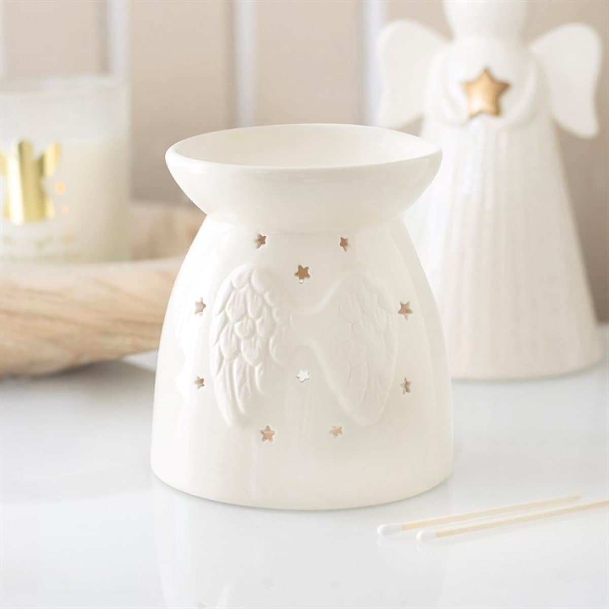 Off-white ceramic oil burner with sculpted angel wings and star cut-outs