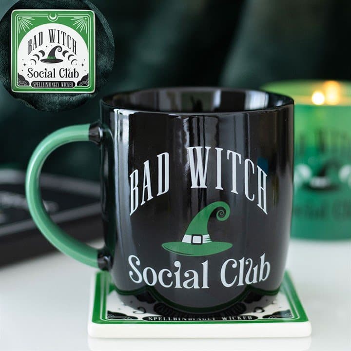 Ceramic mug with a green witch hat design beside a matching coaster