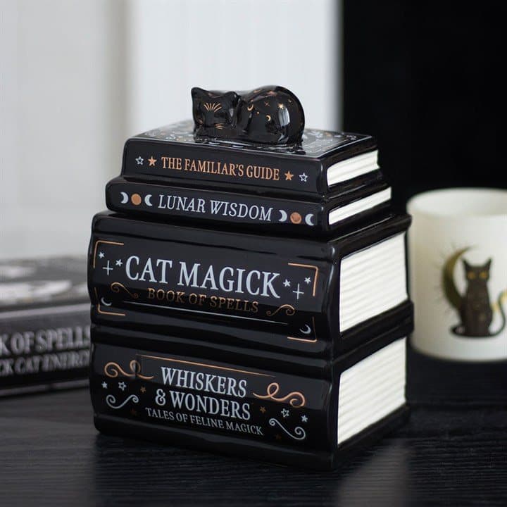 Ceramic oil burner shaped as a stack of books with a black cat on top