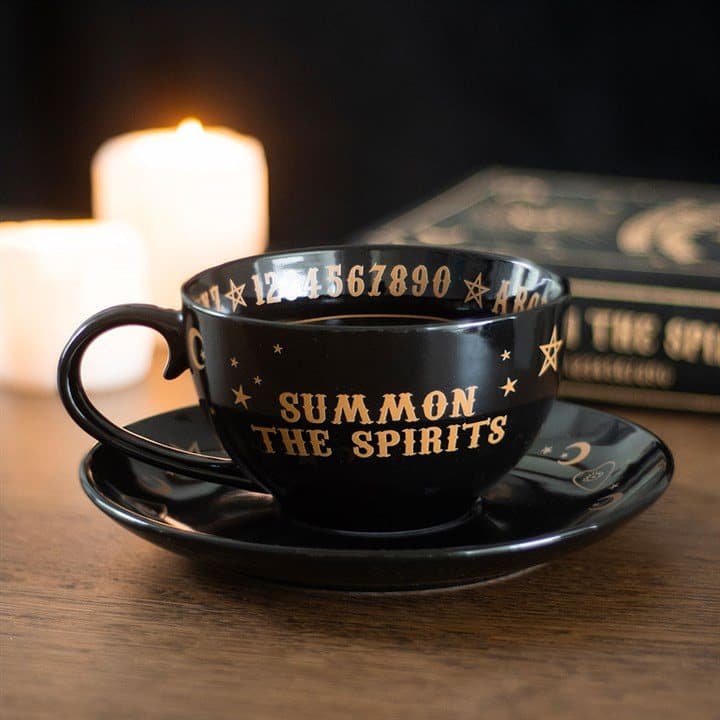 Black and gold ceramic teacup and saucer with a talking board design