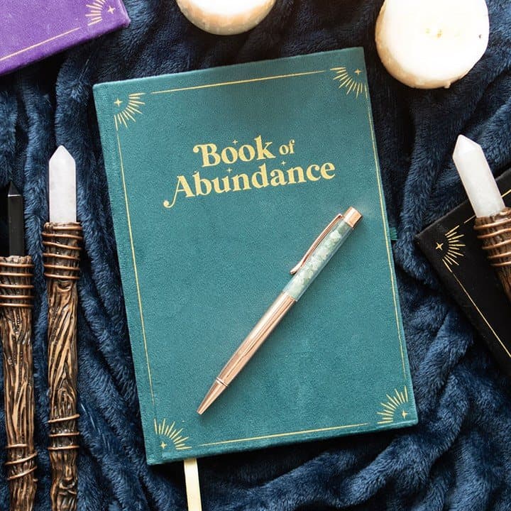 Green journal with gold cover detailing beside a green aventurine crystal pen