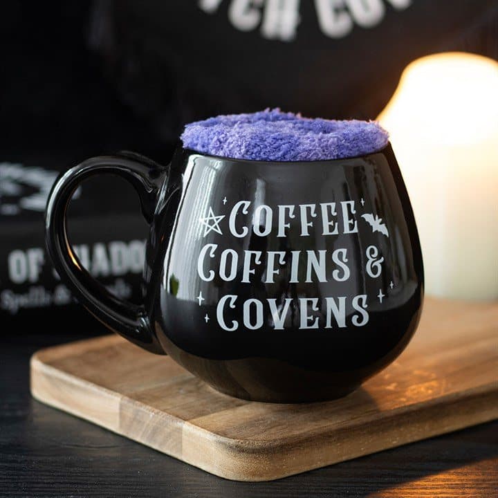 Cauldron-shaped mug with soft purple socks and Coffee, Coffins & Covens text
