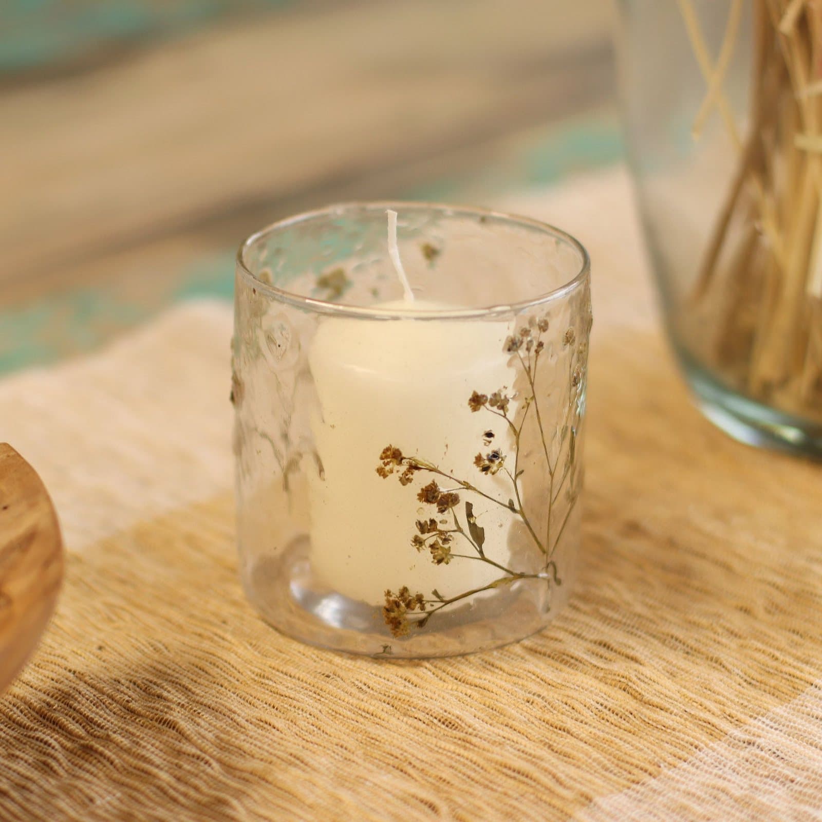 Cylindrical glass candle holder with dried flowers sealed in the glass