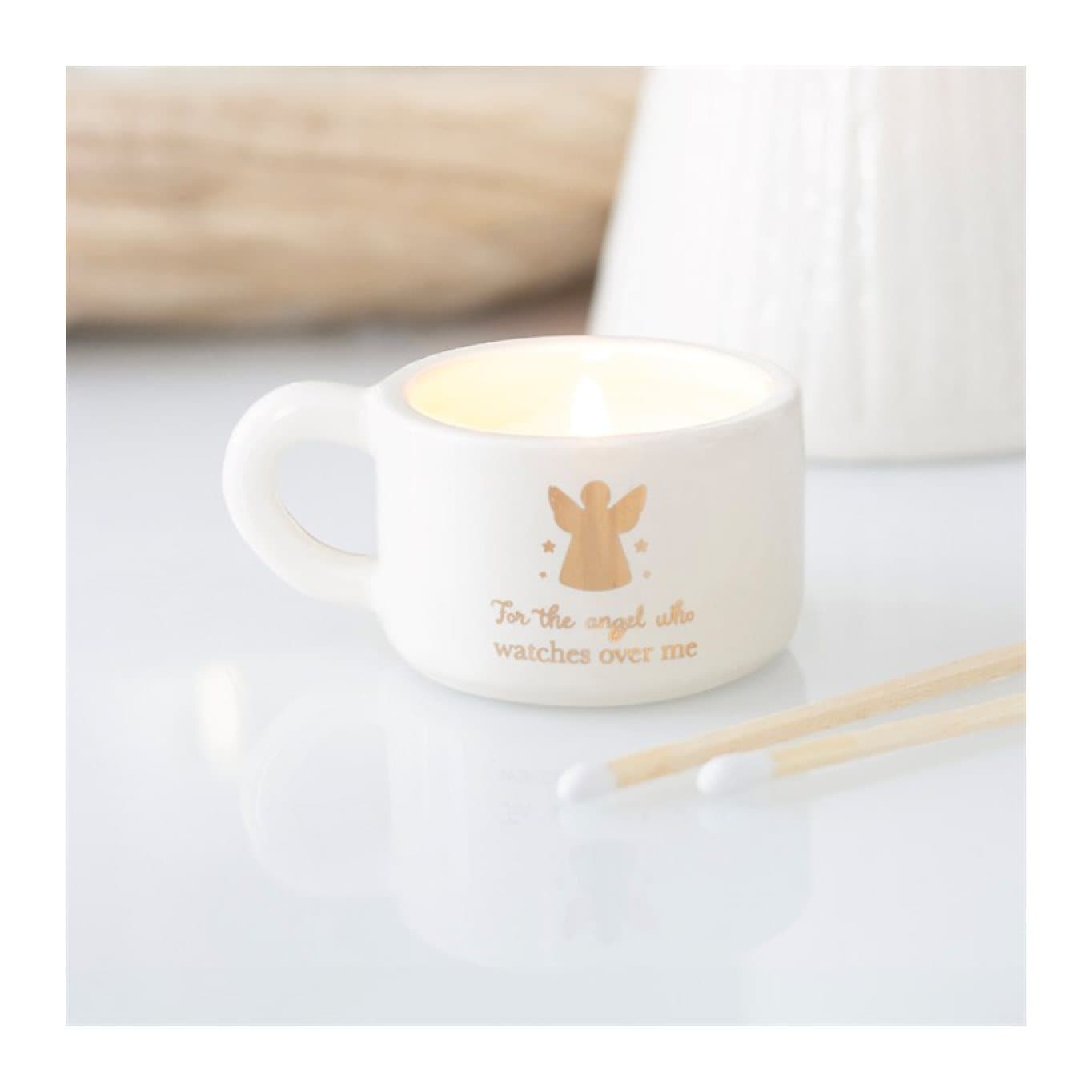 Off-white ceramic tealight holder with a metallic gold angel and a handle