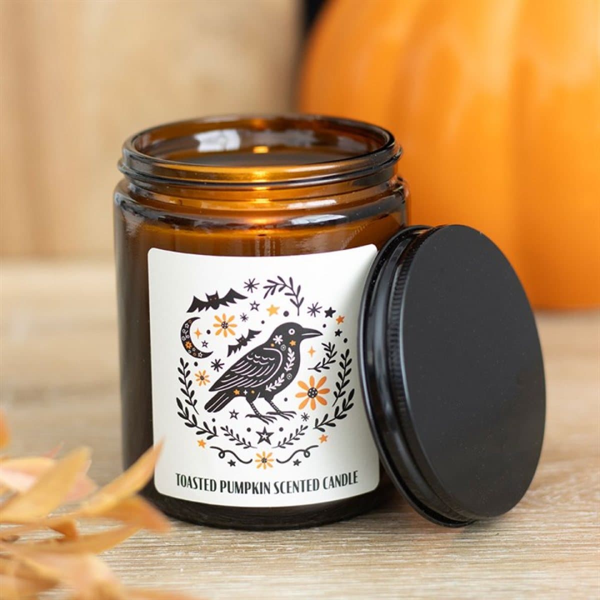 Toasted pumpkin candle in a brown apothecary-style jar with a folk raven design