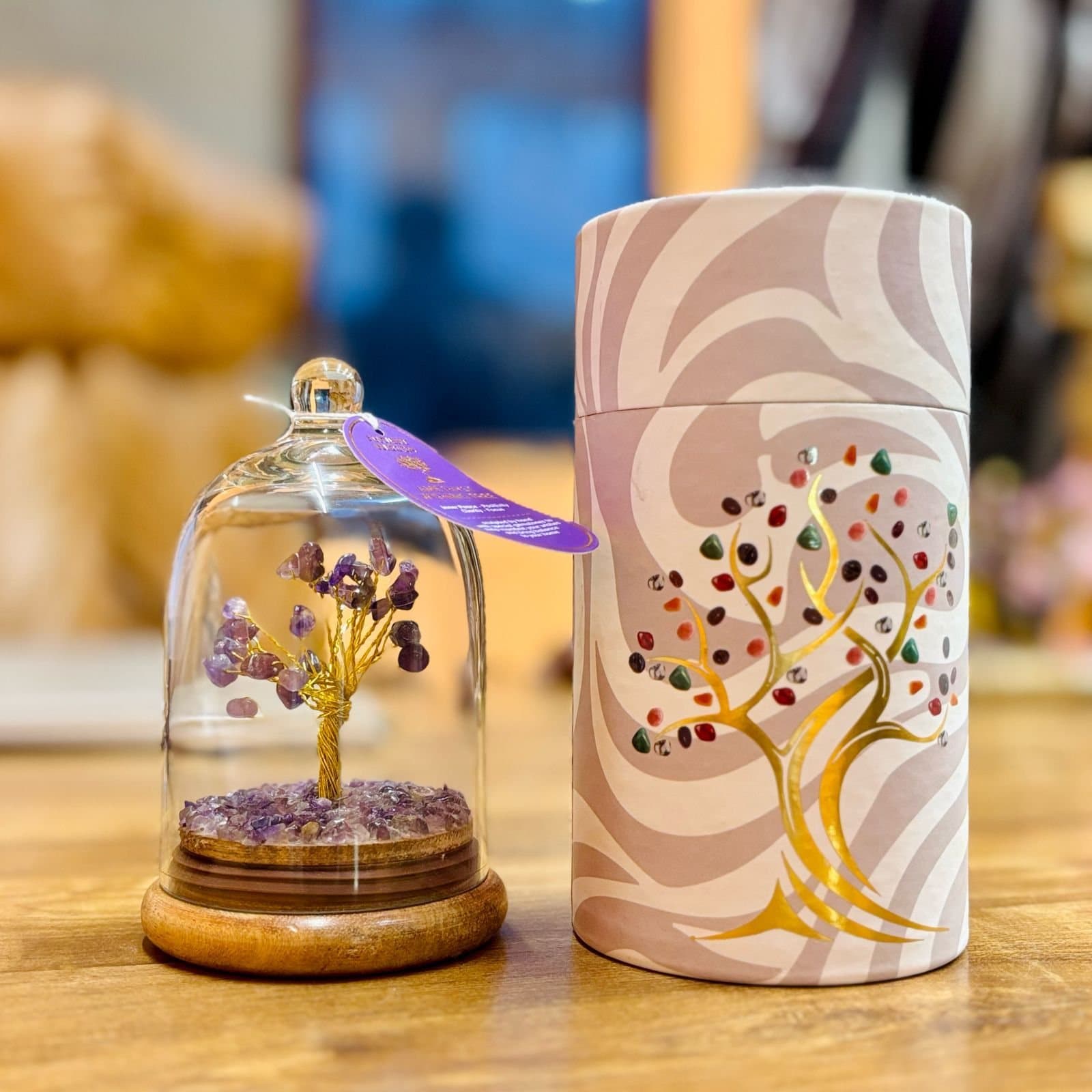 Amethyst gemstone tree under a glass dome on a wooden base