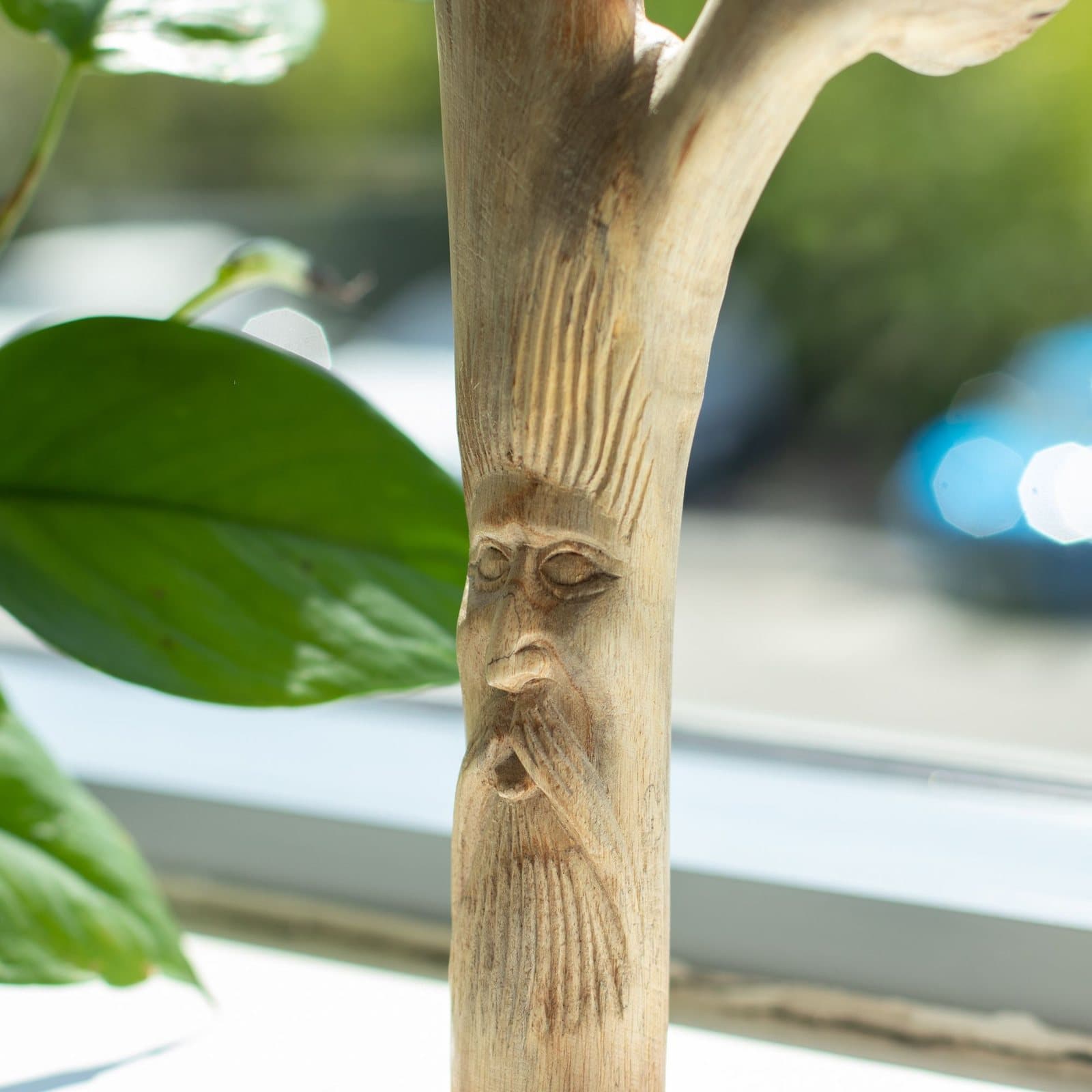 Greenman face carved into an upright natural wooden branch