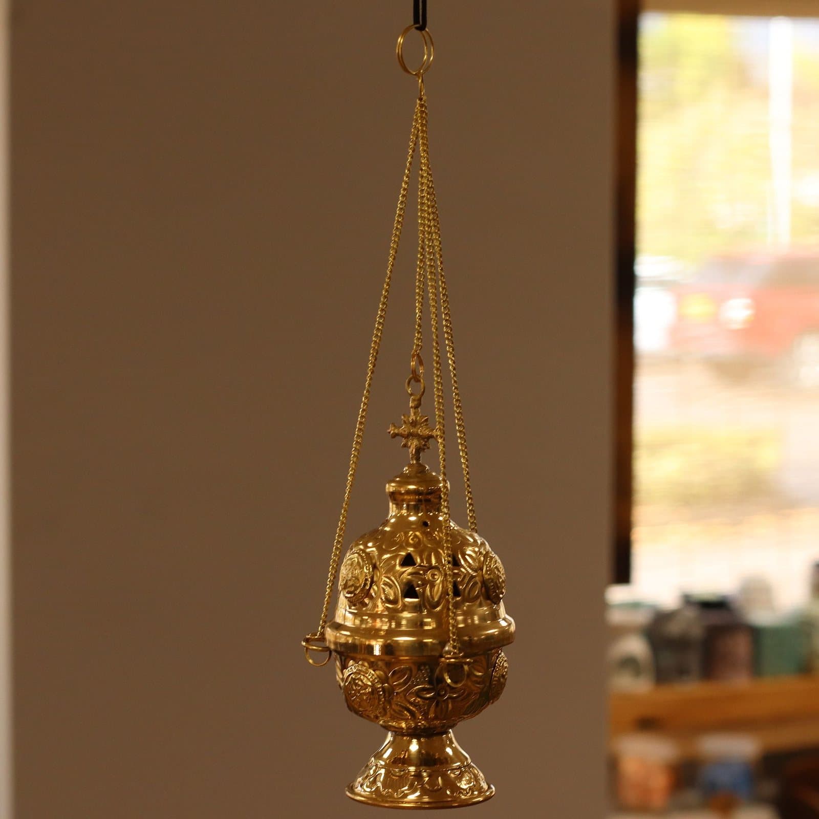 Hanging brass incense burner with a lidded body on a chain