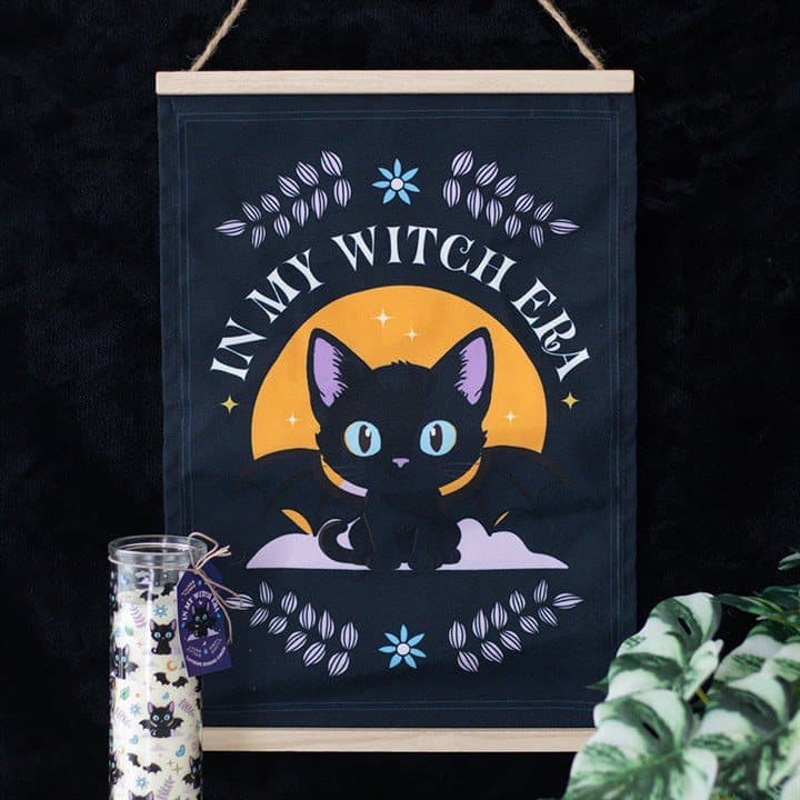 Fabric wall hanging reading In My Witch Era with a bat-winged black cat