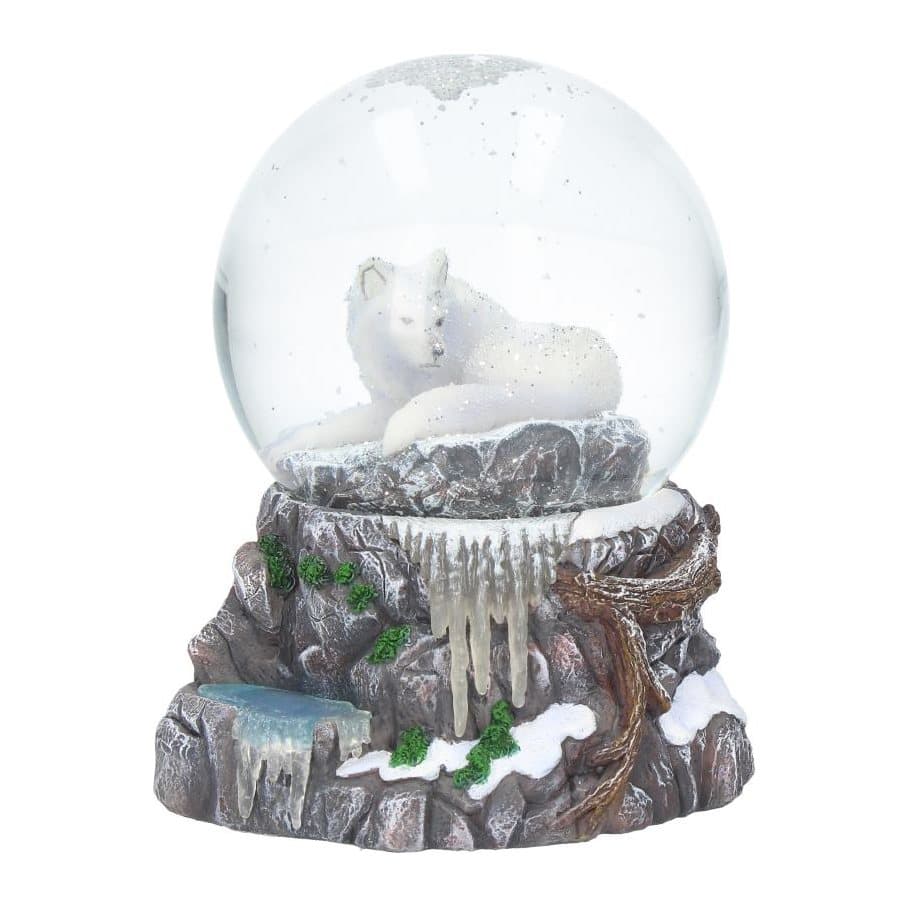 Snow globe of a white wolf under a full moon on snowy rocks