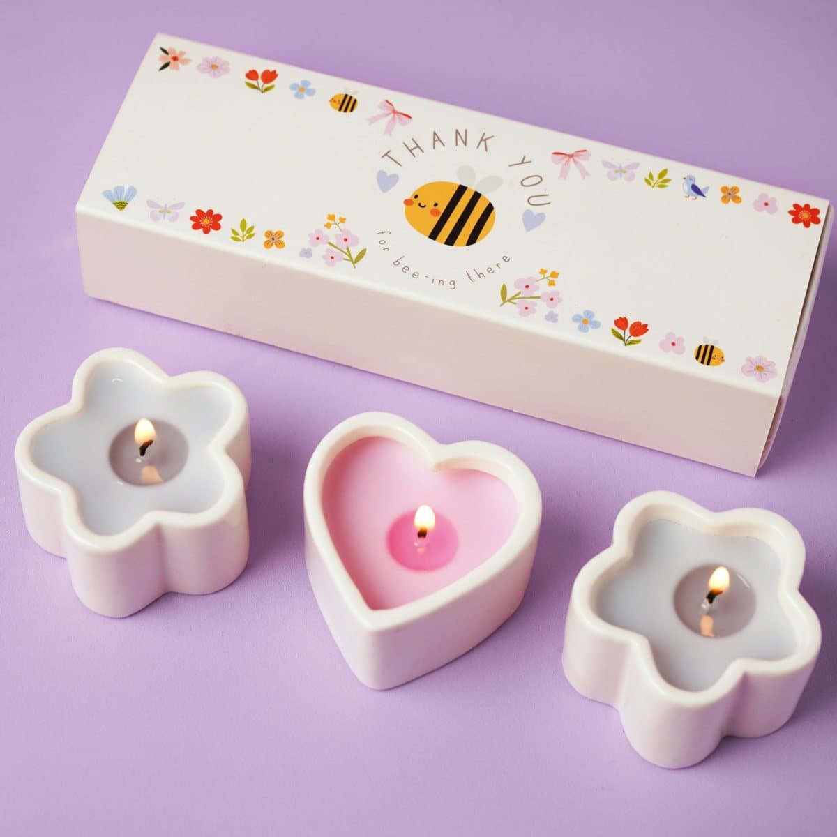 Three mini candles in heart and flower-shaped ceramic holders with a patterned box