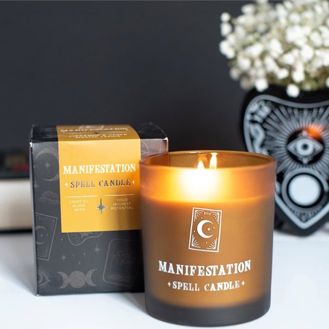 Cinnamon and clove spell candle in a golden glass jar with a tarot-inspired design