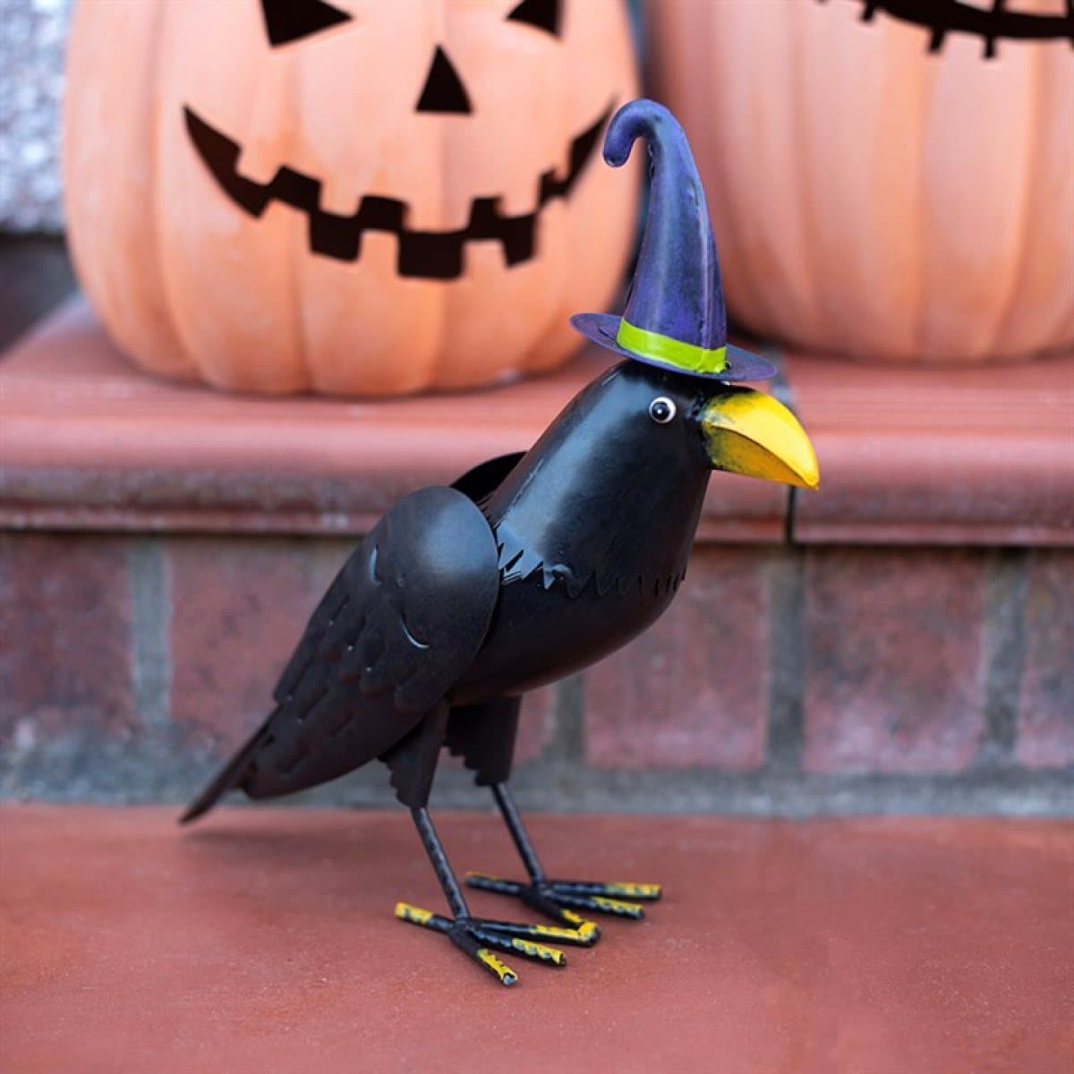 Metal raven ornament wearing a tall witch hat with a bright beak