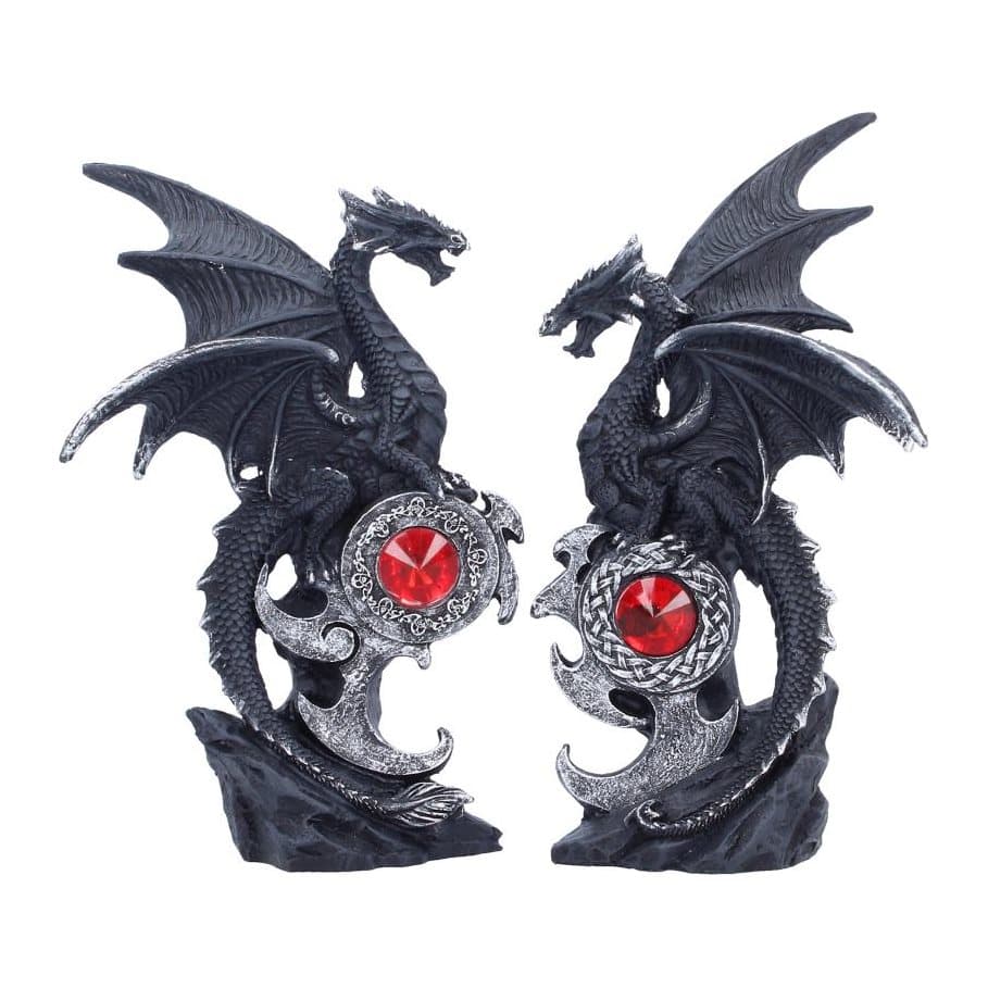 Two black dragon figurines facing each other on a dark rocky base with a red gemstone