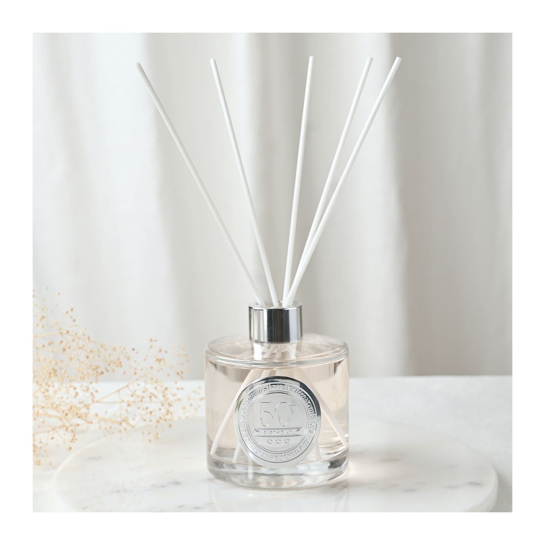 Clear glass sandalwood diffuser with embossed 50 seal and white reed sticks