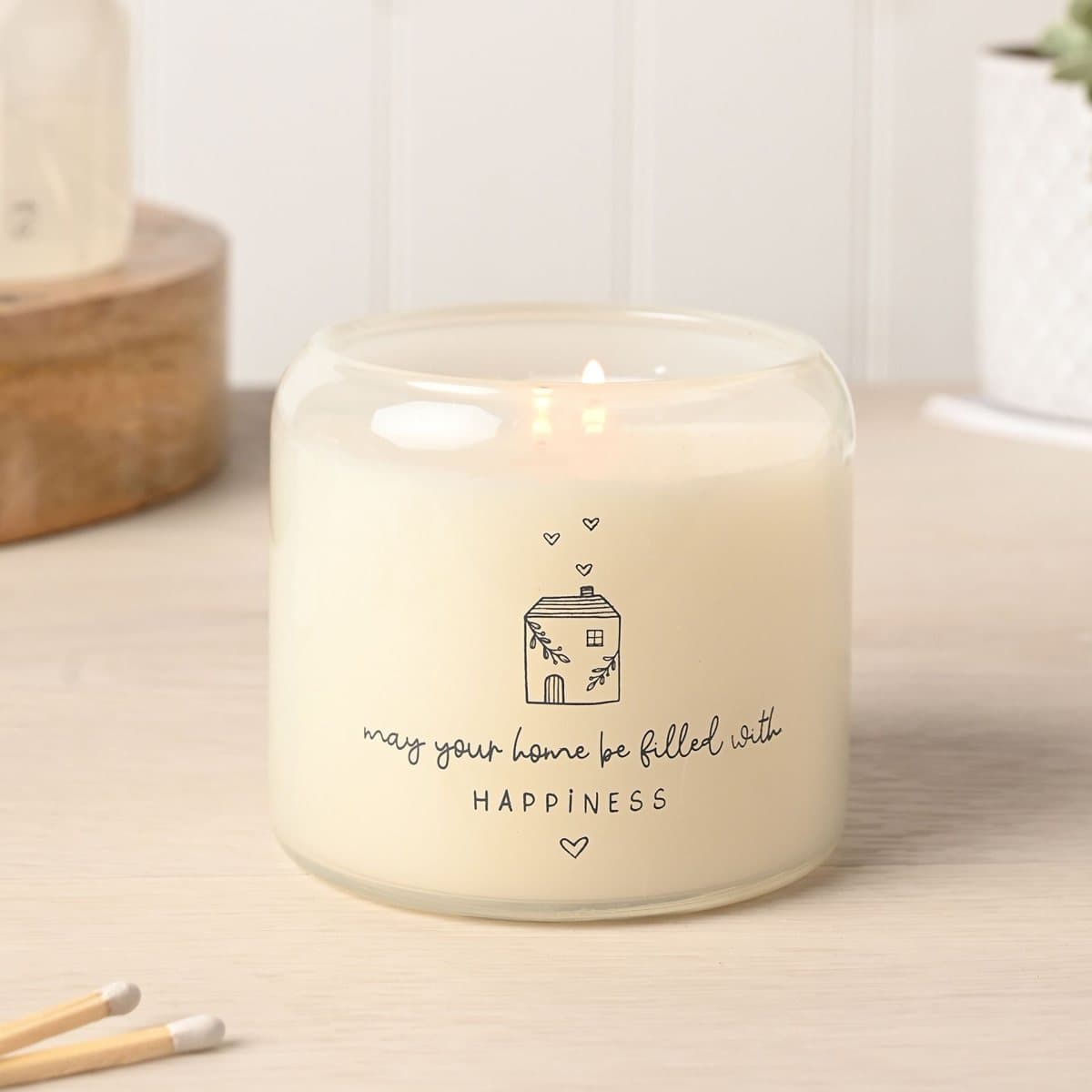 Happy Home double wick candle beside a soft neutral gift box with house illustrations