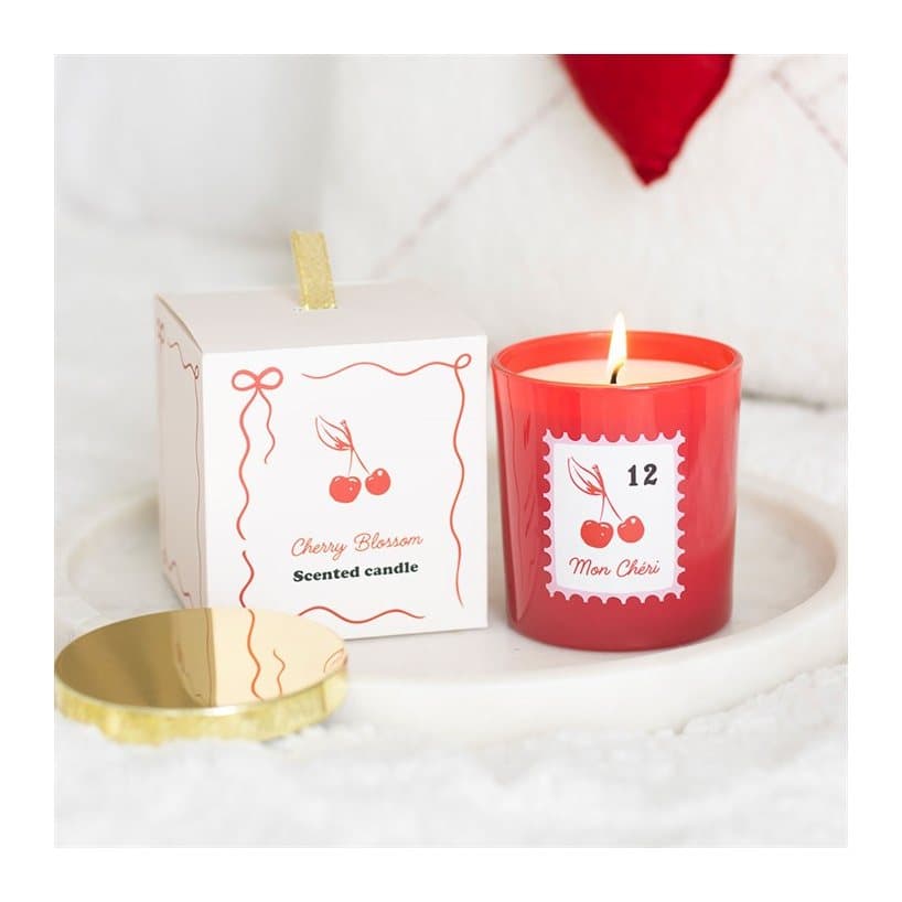 Cherry-red glass jar candle with a gold lid and postage stamp-inspired label