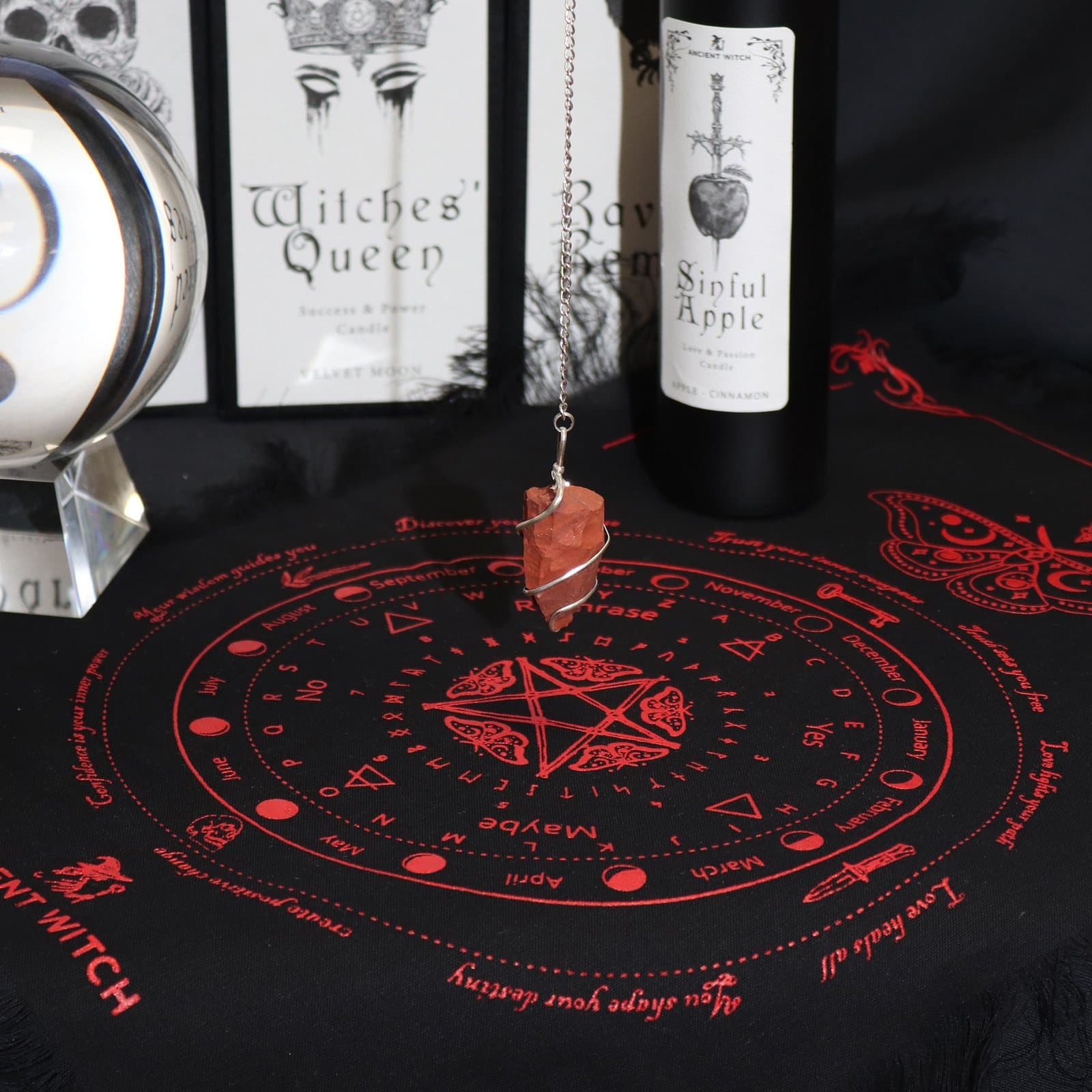 Black cotton cloth with a red moth above a pendulum divination layout