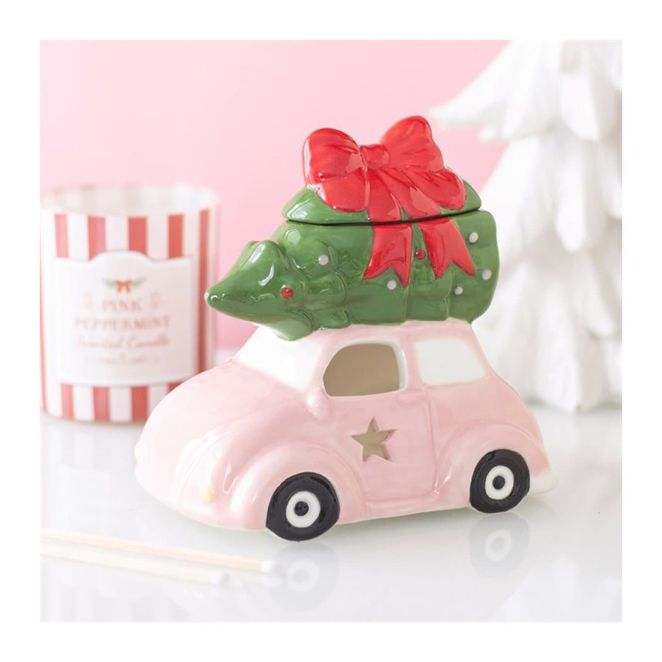 Ceramic oil burner designed as a pink car carrying a Christmas tree with a red bow