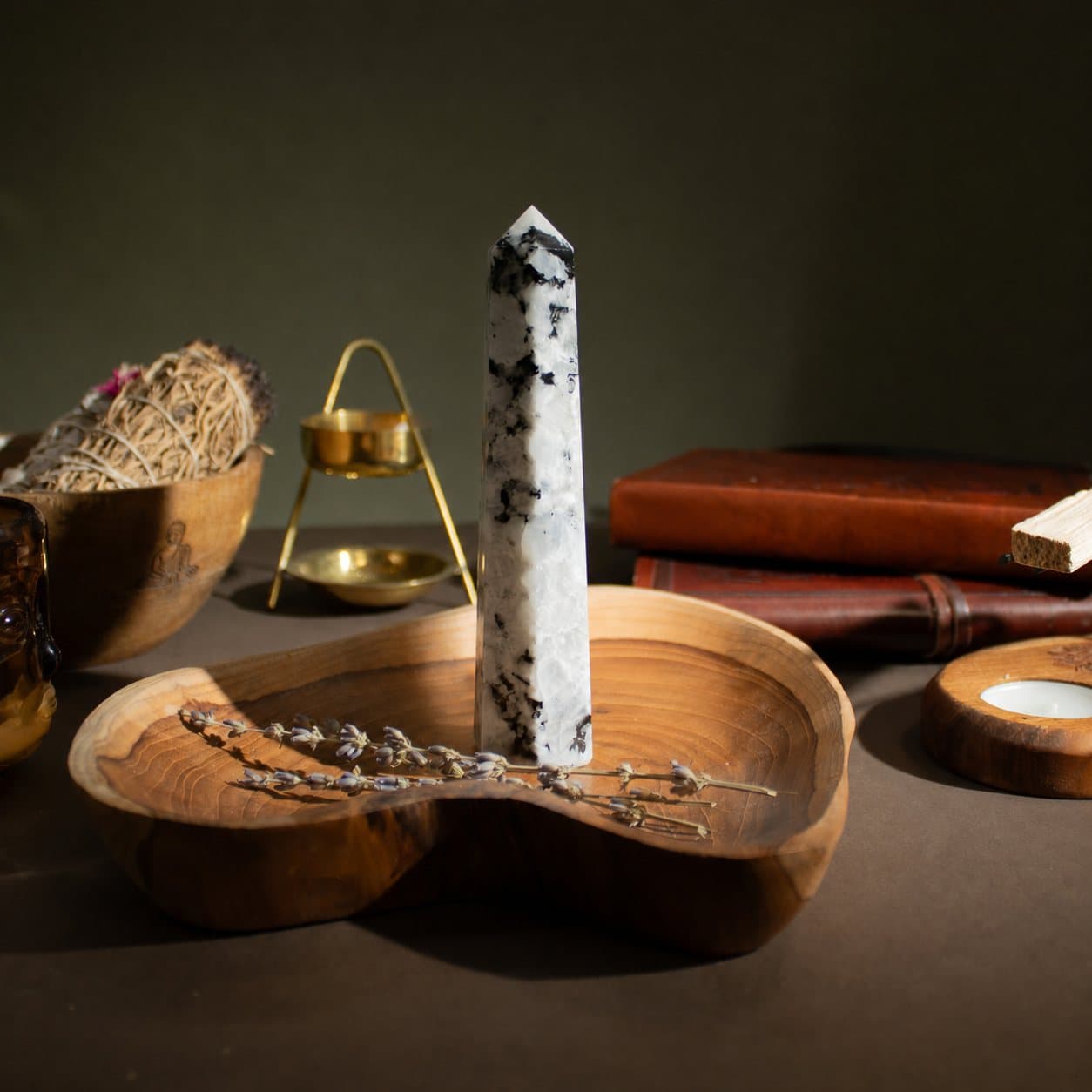 Polished rainbow moonstone six-face obelisk point with milky tones and colour flashes