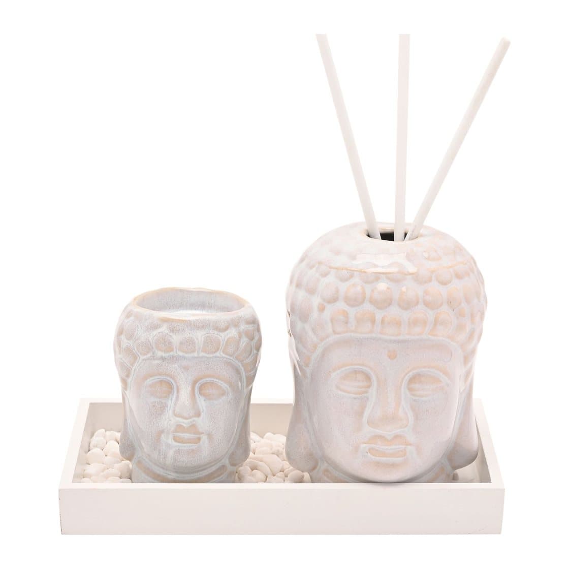Two white ceramic Buddha heads with pebbles on a white tray