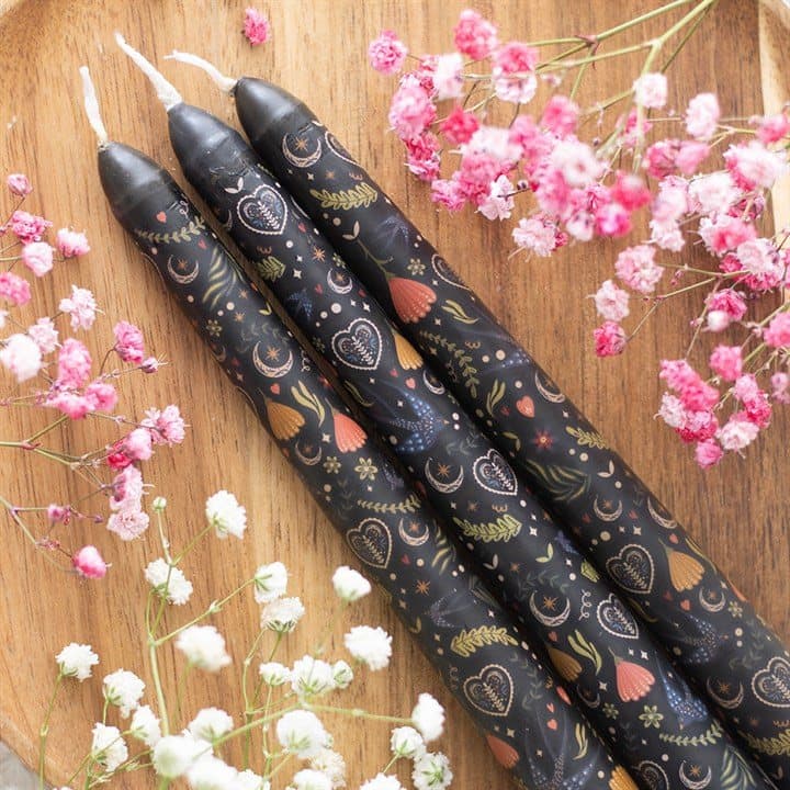 Three black taper candles with a folk-inspired print in a window box