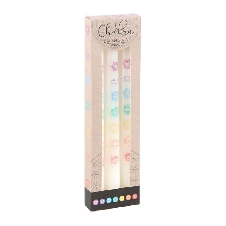 Three white taper candles featuring the colours of the seven chakras