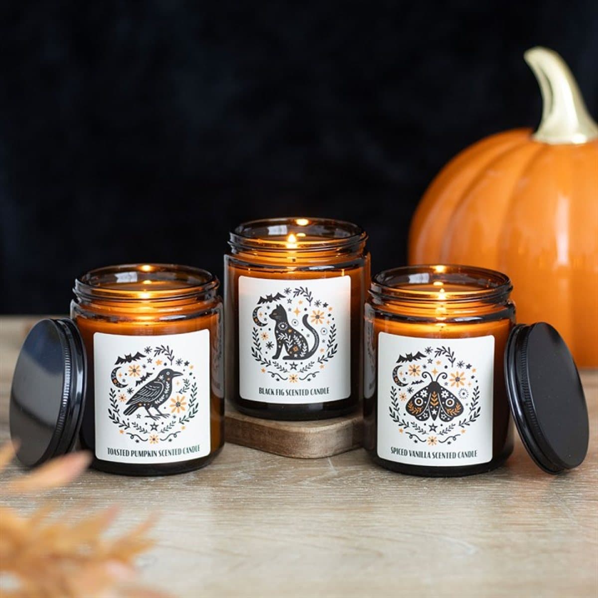 Three folk-design scented candles in amber apothecary-style jars