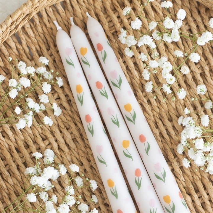 Three taper candles with a tulip print in a window box