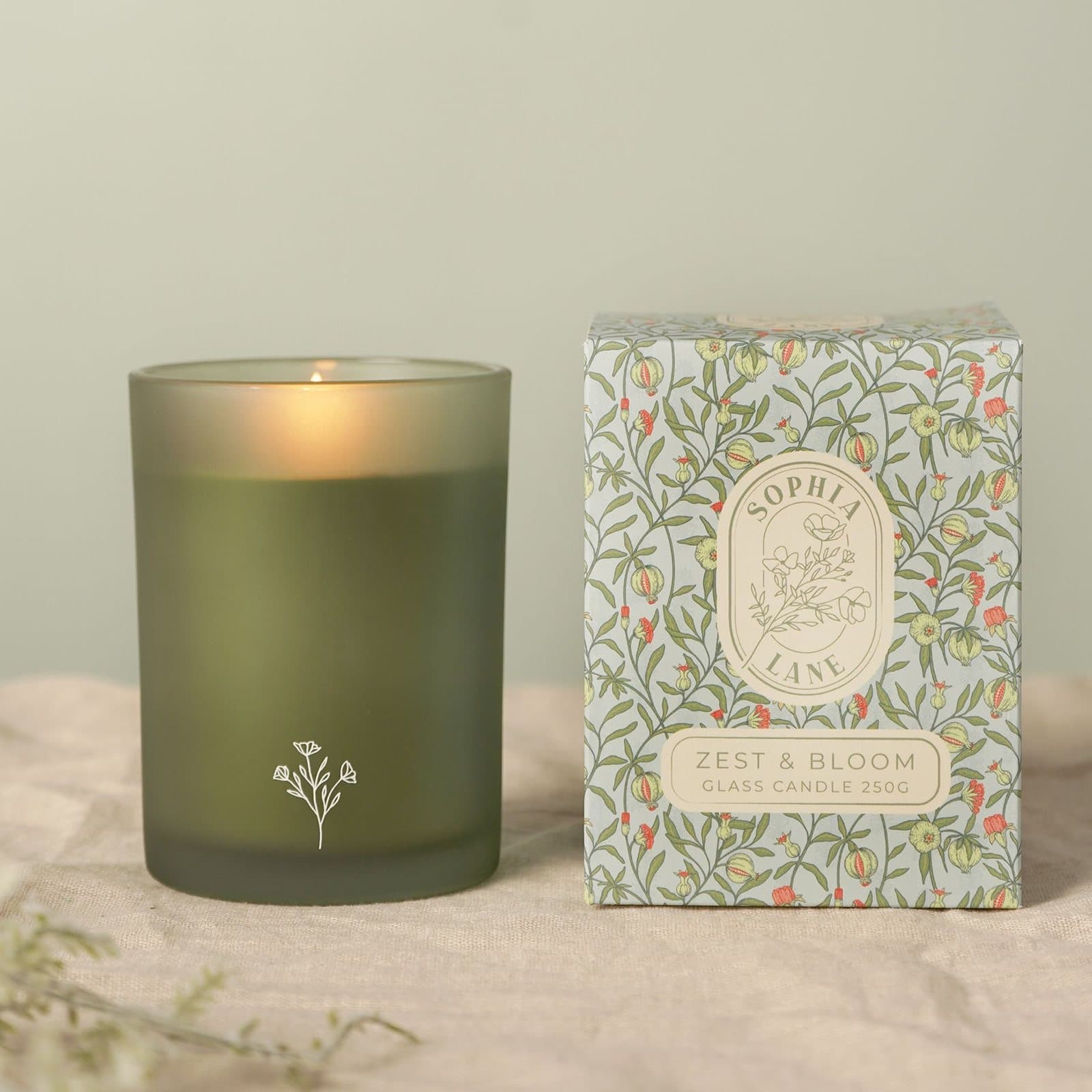 Zest & Bloom green glass floral candle beside its floral-patterned box