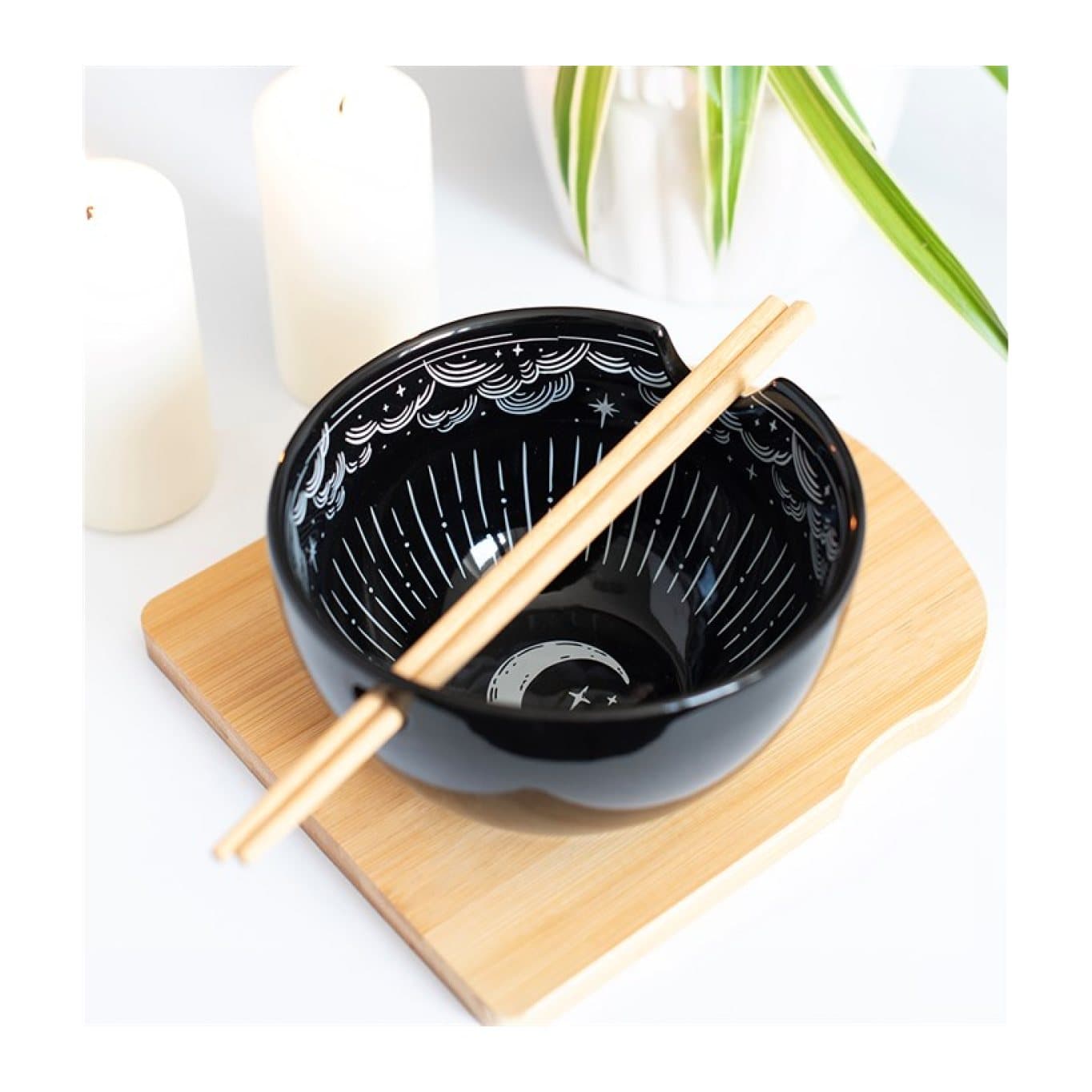 Black ceramic noodle bowl with moon and star details and wooden chopsticks