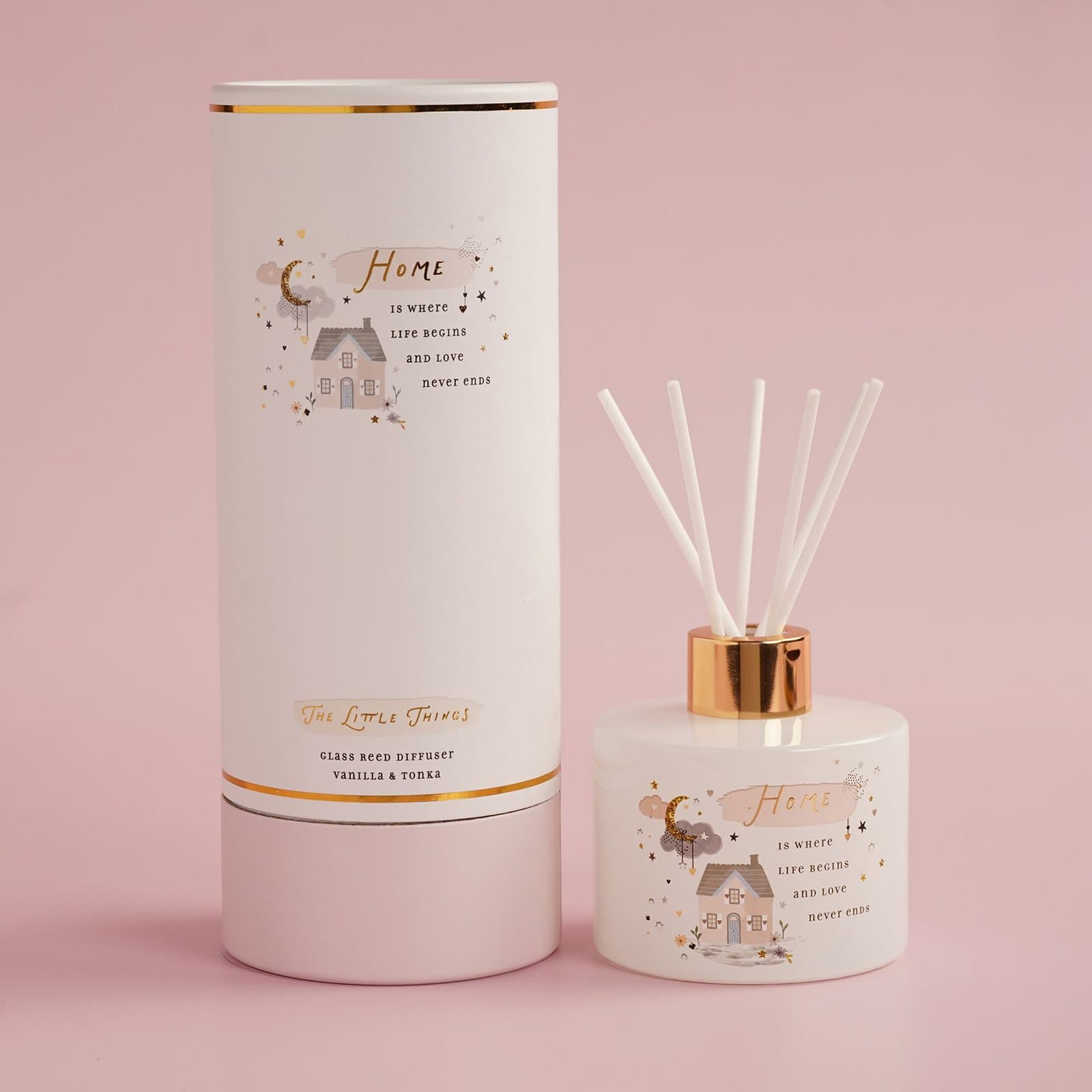 Glass reed diffuser with a home message beside its cylindrical gift box