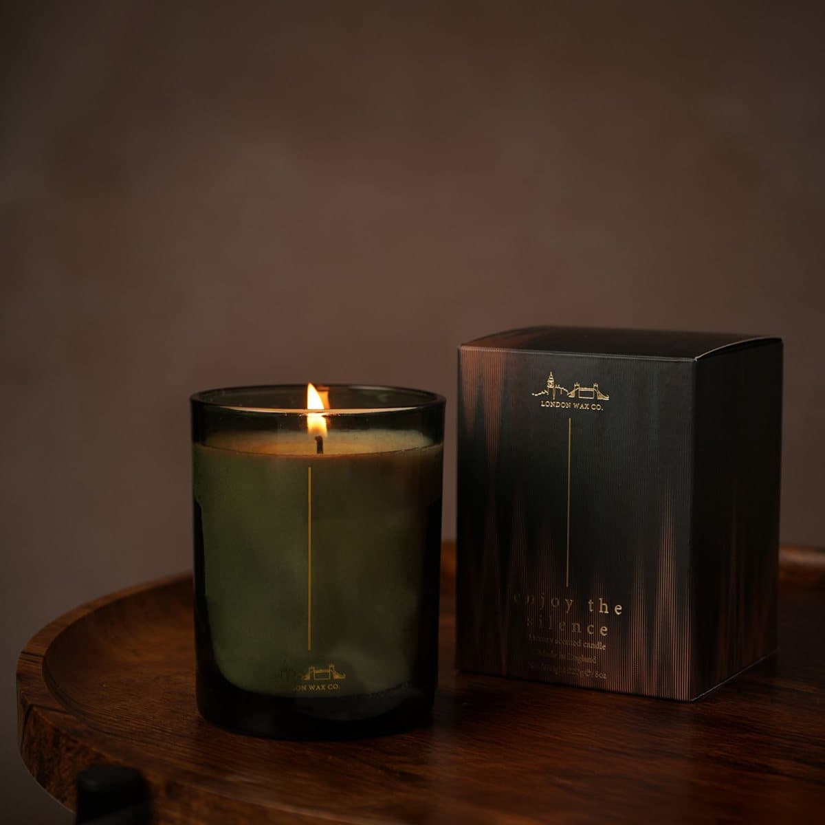 Enjoy The Silence candle in a deep green glass jar with black lid