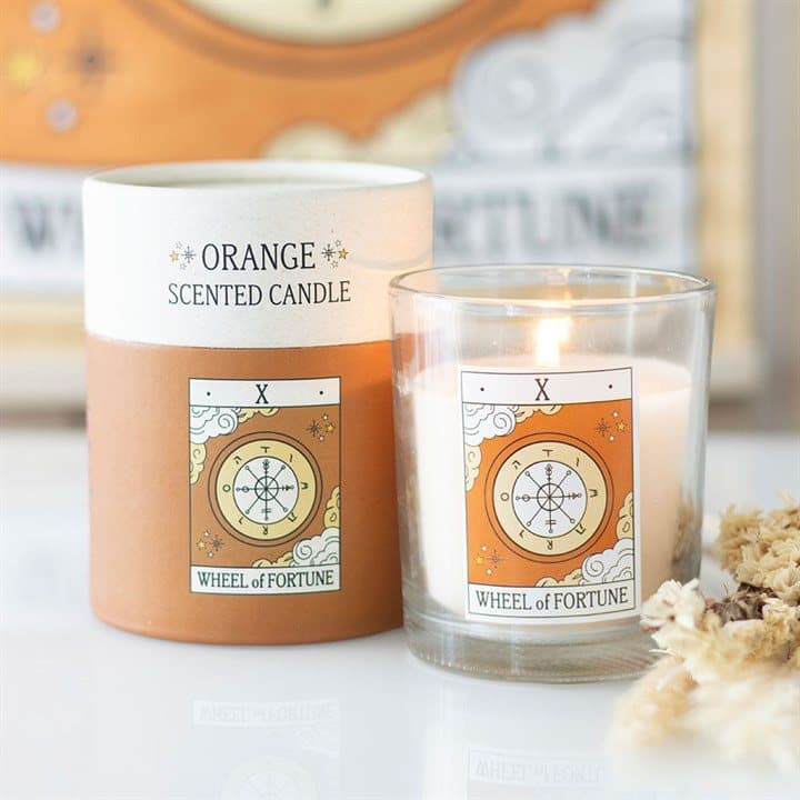 Orange candle with a tan Wheel of Fortune tarot card design