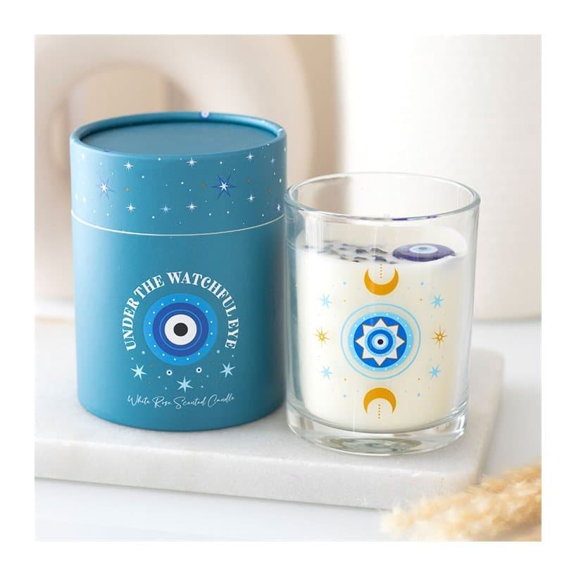 White rose jar candle with an all seeing eye, moons and stars, beside a turquoise box