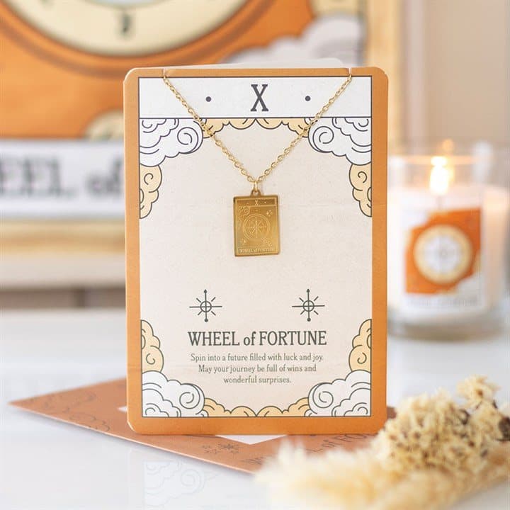 Gold-toned Wheel of Fortune tarot pendant necklace on an illustrated greeting card