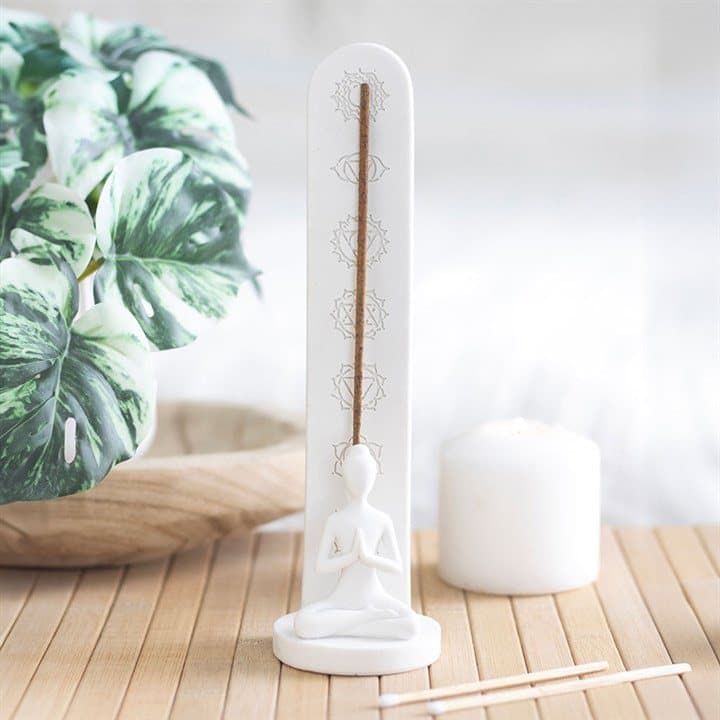 White ceramic incense stick holder with chakra symbols and a lotus pose figure