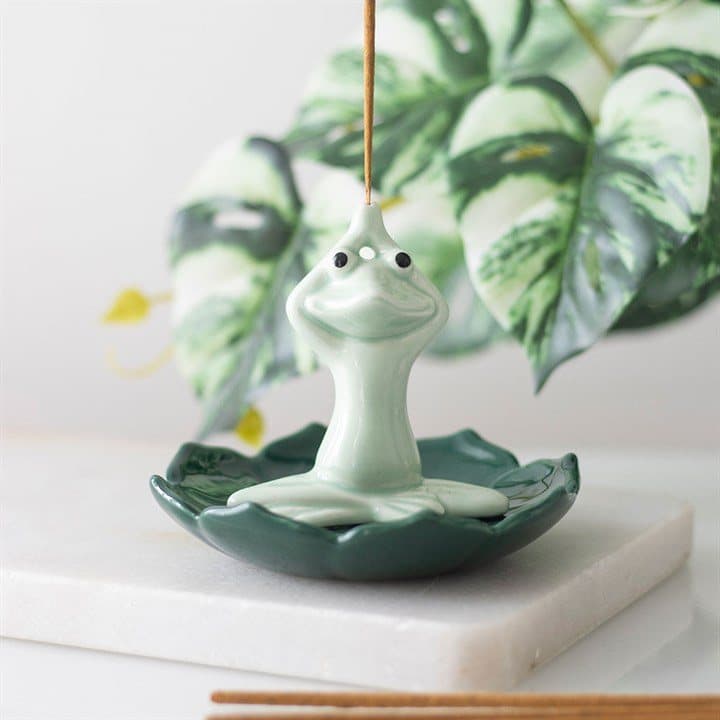 Ceramic yogi frog seated on a green lotus flower, an incense stick holder